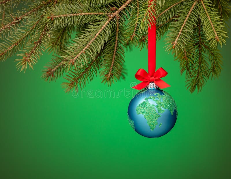 Globe christmas ornament hanging over green. Peace on Earth, eco friendly or winter vacation travel concept