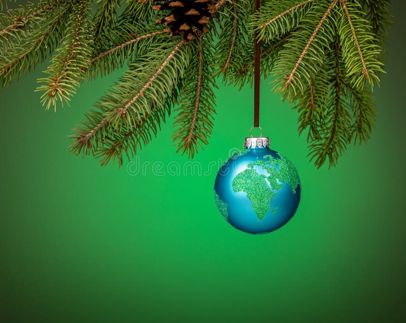 Globe christmas ornament hanging from a tree branch on green