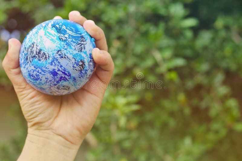 Globes in the hands of Background blurred trees free space sunlight abstract earth nature blue stock photo