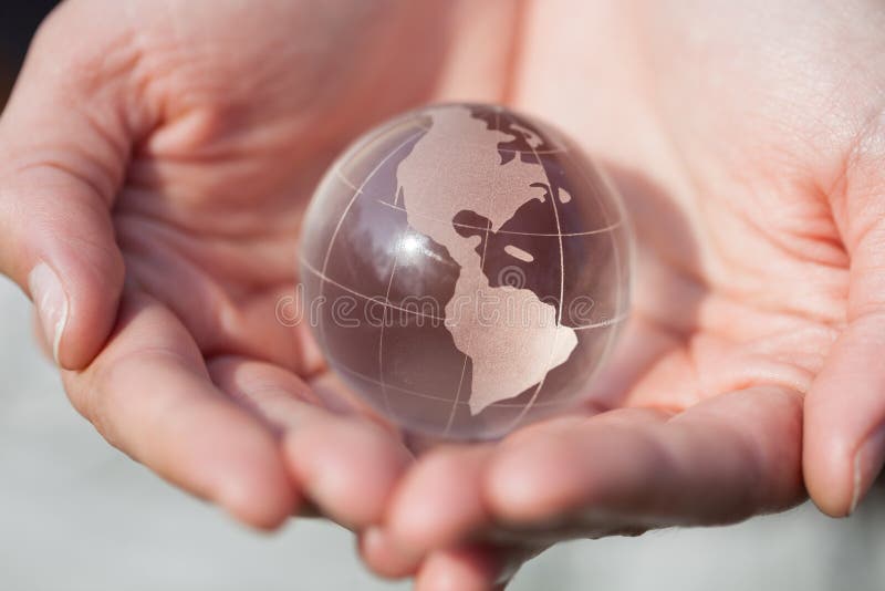 Globo di modello di cristallo della tenuta in mani con attenzione fotografia stock libera da diritti Globo di modello di cristallo della tenuta in mani con attenzione fotografia stock libera da diritti