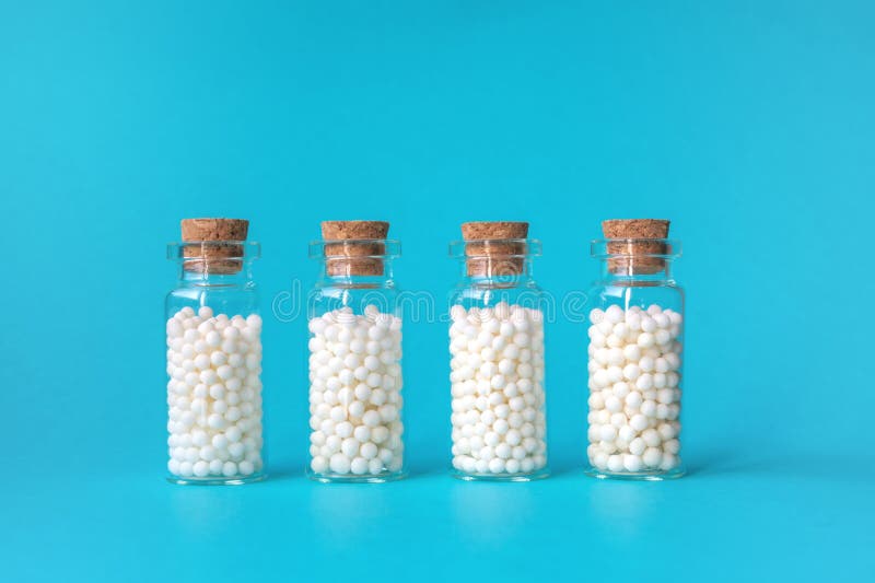 Globuli omeopatici in quattro bottiglie di vetro su fondo blu Erbe alternative della medicina di omeopatia, sanità e fotografia stock Globuli omeopatici in quattro bottiglie di vetro su fondo blu Erbe alternative della medicina di omeopatia, sanità e fotografia stock