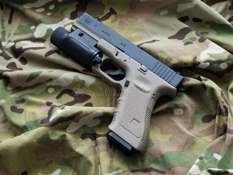 Los Angeles, CA, USA - September 11, 2015: Glock 17 semi-automatic 9x19mm pistol and a Multicam pattern background. Los Angeles, CA, USA - September 11, 2015: Glock 17 semi-automatic 9x19mm pistol and a Multicam pattern background