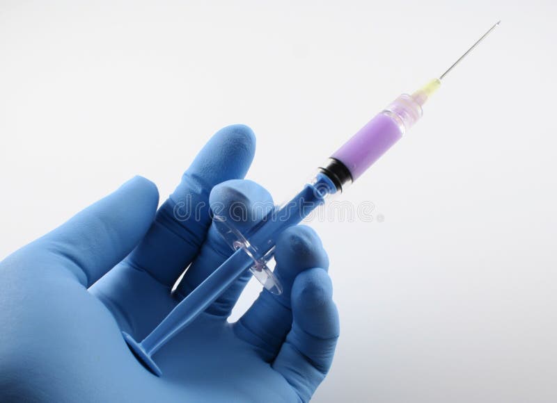 Gloved hand with blue syringe