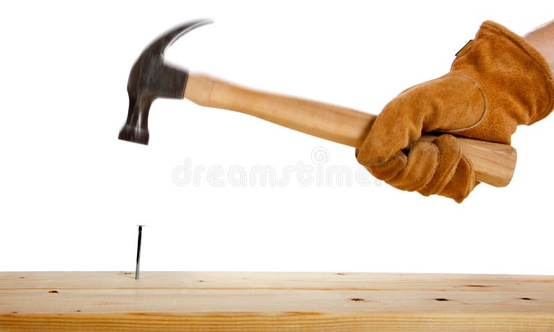 A gloved hand hammering a nail stock photo