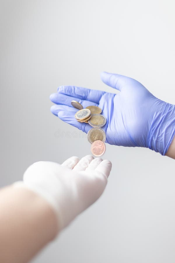Gloved hand offering a few euro coins. Concept of financial crisis after the coronavirus covid19 stock image Gloved hand offering a few euro coins. Concept of financial crisis after the coronavirus covid19 stock image