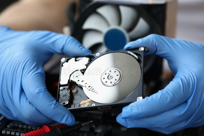 Gloved hands holding computer hard drive device royalty free stock photography