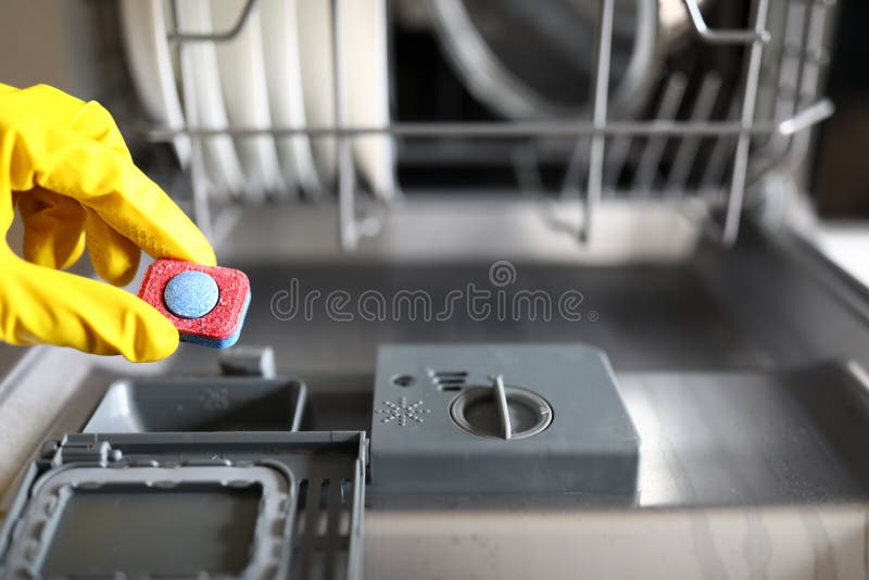 Gloved hands holding dishwasher washing tablet royalty free stock images