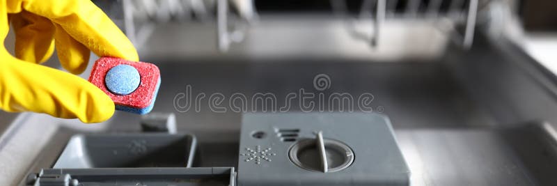 Gloved hands holding dishwasher washing tablet royalty free stock photo