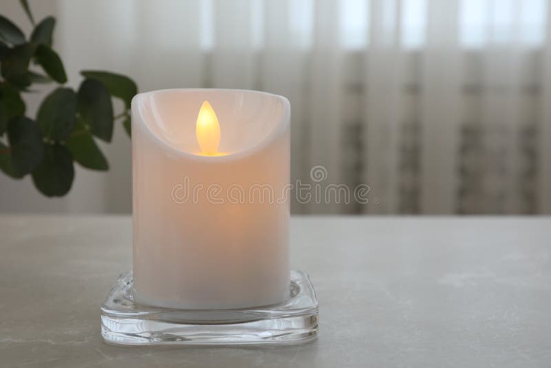 Glowing Decorative LED Candle on Grey Table. Space for Text Stock Image