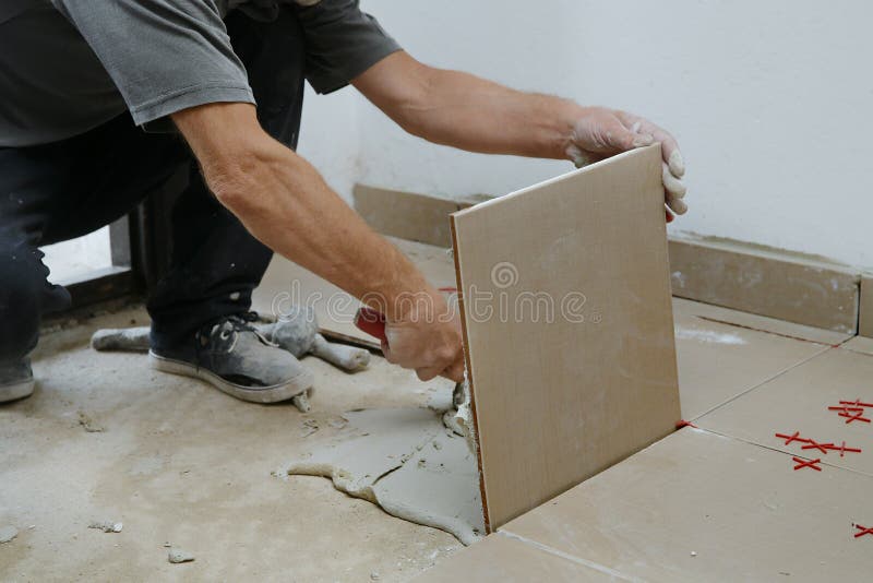 Construction Worker Is Tiling Floor At Home Laying Tiles On The