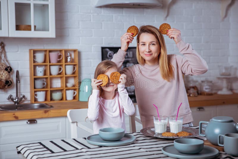 Glückliches kleines Mädchen und ihre schöne junge Mutter frühstücken zusammen in einer weißen Küche Sie haben Spaß und spielen mi stockfotos Glückliches kleines Mädchen und ihre schöne junge Mutter frühstücken zusammen in einer weißen Küche Sie haben Spaß und spielen mi stockfotos