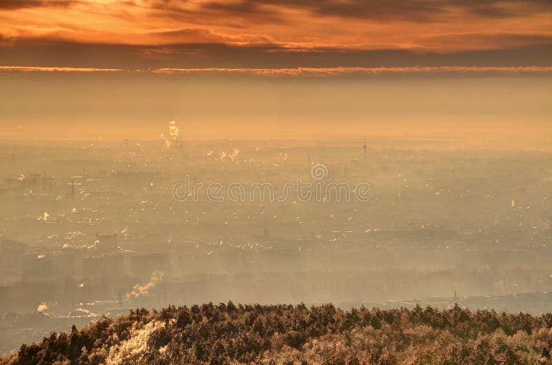 Glowing sunrise over Budapest industrial and residential areas with buildings, towers and chimneys in winter morning mist Angyalfold Zuglo Kobanya districts of Pest from Harmashatarhegy Hungary Europe. Glowing sunrise over Budapest industrial and residential areas with buildings, towers and chimneys in winter morning mist Angyalfold Zuglo Kobanya districts of Pest from Harmashatarhegy Hungary Europe