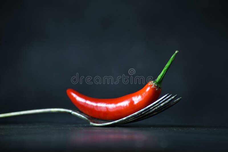 Glödhet chilipeppar på tappninggaffel på svart stenbakgrund royaltyfri foto Glödhet chilipeppar på tappninggaffel på svart stenbakgrund royaltyfri foto