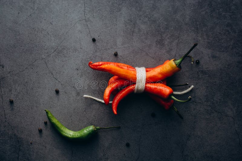 Glödhet grupp för chilichiliespeppar som binds av rad på en grå bakgrund fotografering för bildbyråer Glödhet grupp för chilichiliespeppar som binds av rad på en grå bakgrund fotografering för bildbyråer