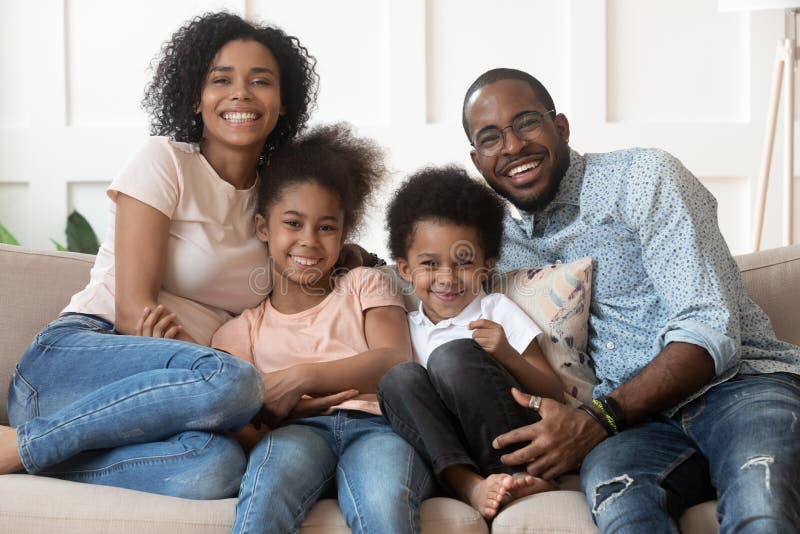 Glückliche afrikanische vierköpfige Familie, die zu Hause Kamera betrachtet
