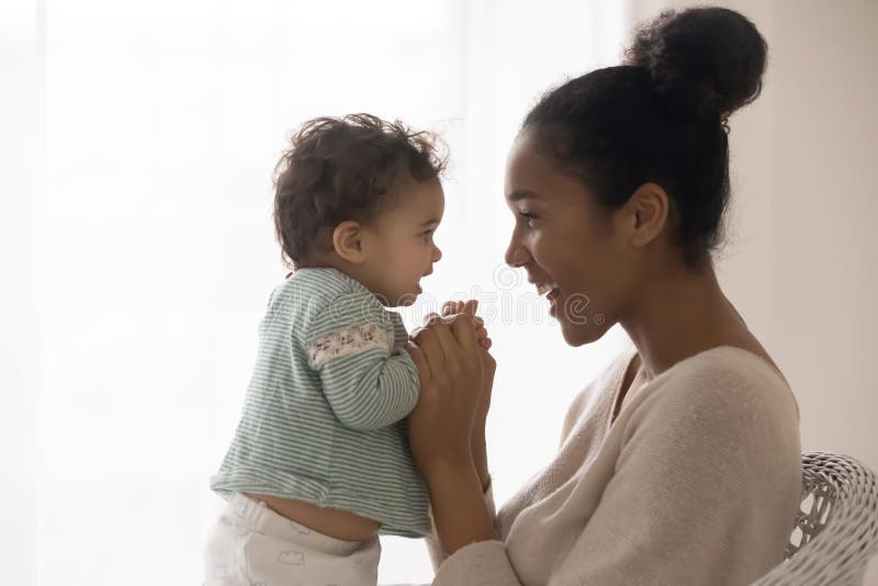Glückliche Afroamerikanermutter und Kleinkindmädchen, die Ausschreibung Moment genießt