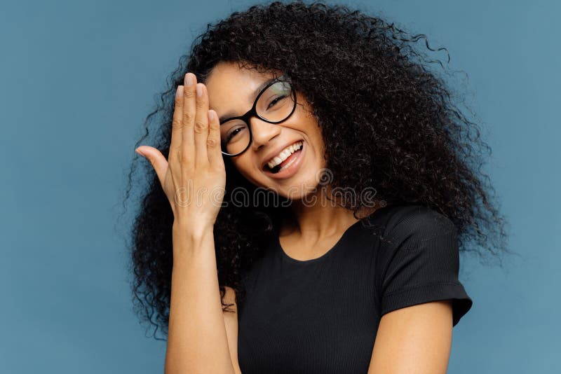 Glückliche afroe-amerikanisch Frau berührt Stirn, kippt Kopf, lächelt glücklich an der Kamera, hat den Innen Spaß, trägt optische stockbilder Glückliche afroe-amerikanisch Frau berührt Stirn, kippt Kopf, lächelt glücklich an der Kamera, hat den Innen Spaß, trägt optische stockbilder