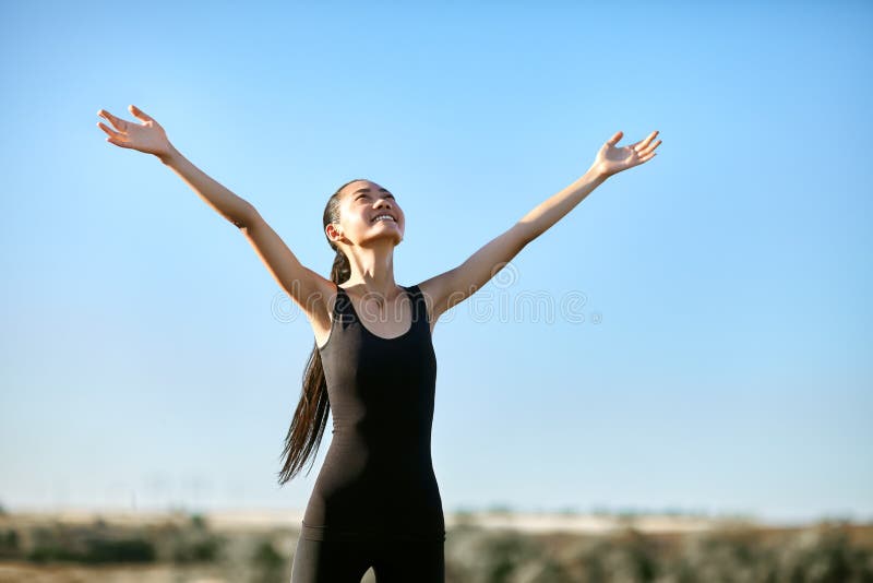 Glückliche Asiatin, die mit den offenen Armen steht, um Sonne zu treffen lizenzfreie stockfotografie Glückliche Asiatin, die mit den offenen Armen steht, um Sonne zu treffen lizenzfreie stockfotografie