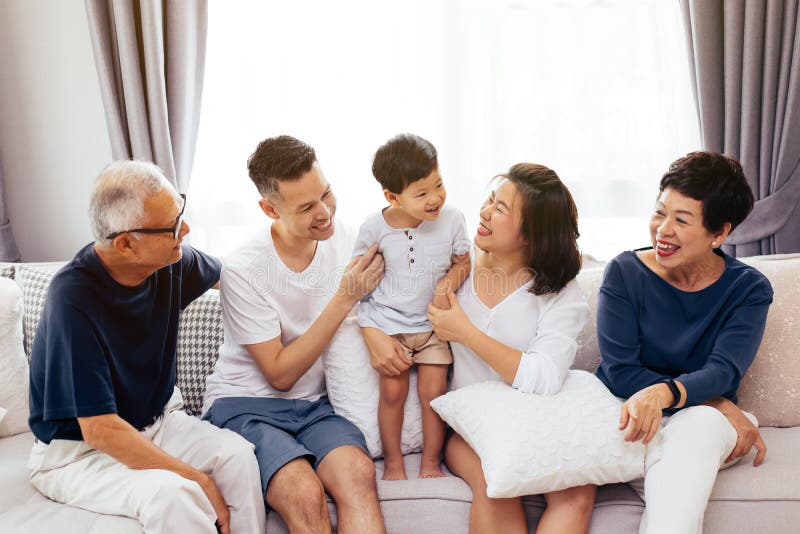 Glückliche asiatische Großfamilie, die zusammen auf Sofa, werfend für Gruppenfotos sitzt auf lizenzfreies stockfoto Glückliche asiatische Großfamilie, die zusammen auf Sofa, werfend für Gruppenfotos sitzt auf lizenzfreies stockfoto