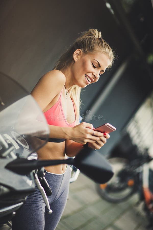 Glückliche blonde junge Frauen, die ihr intelligentes Telefon verwenden lizenzfreie stockbilder Glückliche blonde junge Frauen, die ihr intelligentes Telefon verwenden lizenzfreie stockbilder