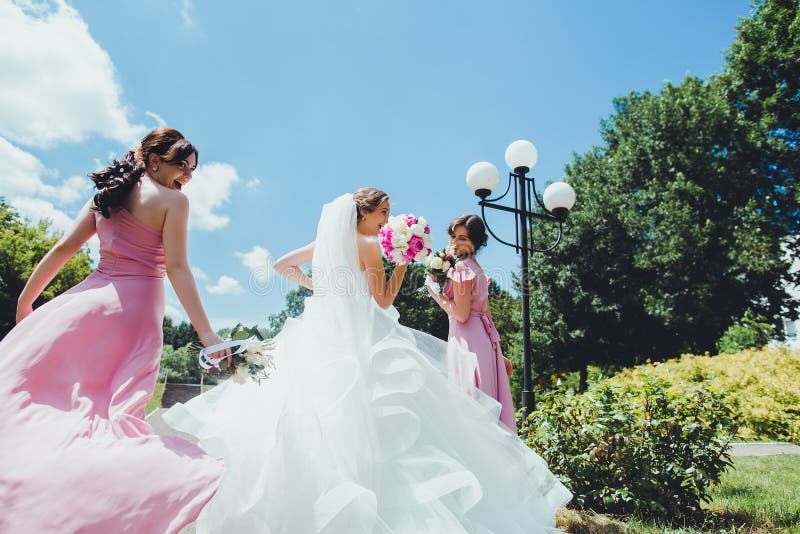 Glückliche Braut mit Brautjungfern im Park am Hochzeitstag lizenzfreie stockbilder Glückliche Braut mit Brautjungfern im Park am Hochzeitstag lizenzfreie stockbilder