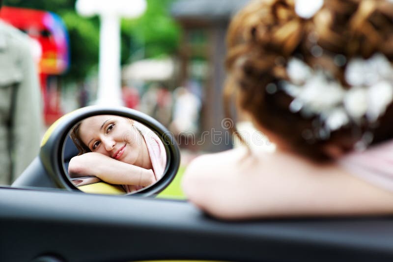 Glückliche Brautblicke im Spiegel des Autos an der Hochzeit gehen lizenzfreies stockfoto Glückliche Brautblicke im Spiegel des Autos an der Hochzeit gehen lizenzfreies stockfoto