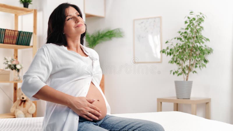 Glückliche brunette schwangere Frauen streicheln Bauch genießen ruhige Ruhe entspannen im Bett zu Hause