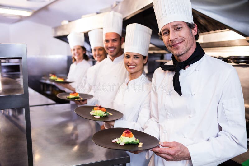 Glückliche Chefs, die ihre Lebensmittelplatten darstellen lizenzfreies stockfoto Glückliche Chefs, die ihre Lebensmittelplatten darstellen lizenzfreies stockfoto