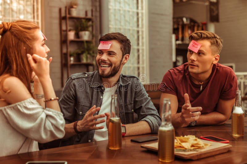 Glückliche drei Freunde, die ein Lachen teilen und zusammen hedbanz spielen stockbilder Glückliche drei Freunde, die ein Lachen teilen und zusammen hedbanz spielen stockbilder