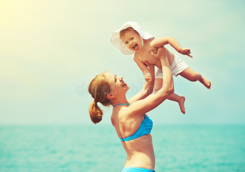 Glückliche Familie auf dem Strand Mutter werfen oben Babytochter und pl