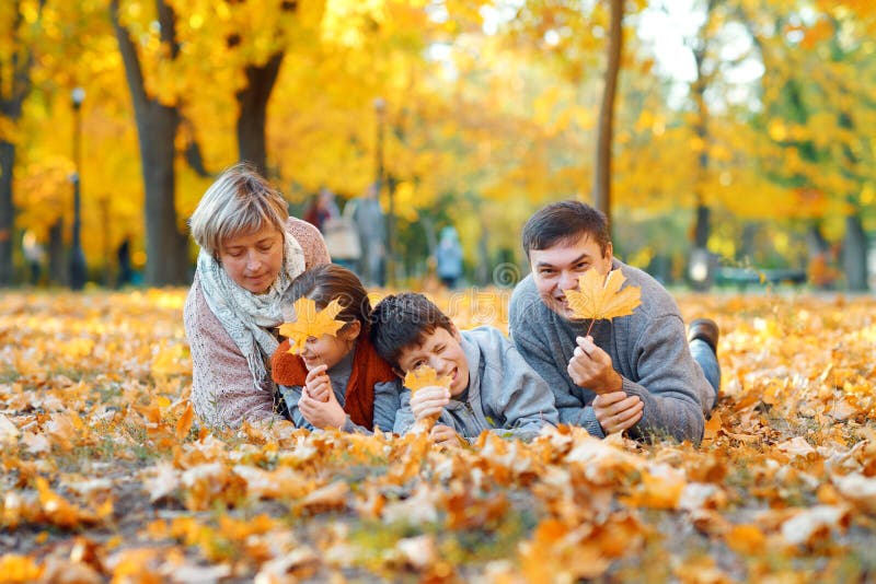 Glückliche Familie auf gefallenen Blättern liegen, spielen und Spaß im Herbststädtpark. Kinder und Eltern haben gemeinsam eine stockbilder Glückliche Familie auf gefallenen Blättern liegen, spielen und Spaß im Herbststädtpark. Kinder und Eltern haben gemeinsam eine stockbilder