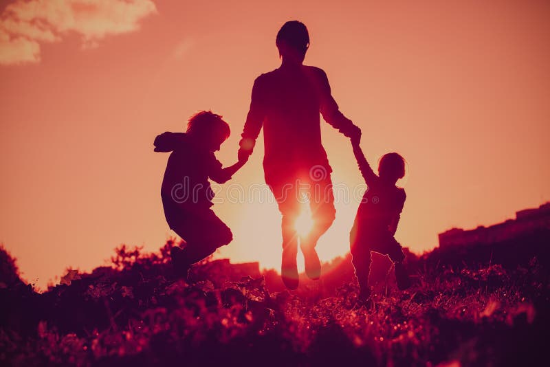 Glückliche Familie - bringen Sie mit dem Sohn und Tochter hervor, die von der Freude in der Sonnenuntergangnatur springen