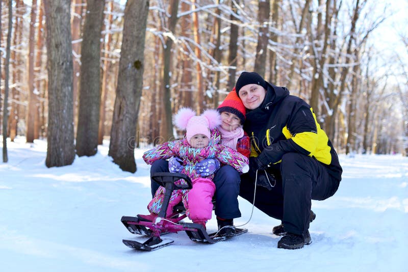 Glückliche Familie, die auf einem Schlitten im Winter sitzt lizenzfreie stockfotos Glückliche Familie, die auf einem Schlitten im Winter sitzt lizenzfreie stockfotos