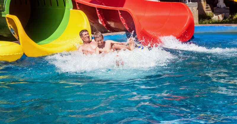 Glückliche Familie, die das Wasserparkdia genießt stockfotos Glückliche Familie, die das Wasserparkdia genießt stockfotos