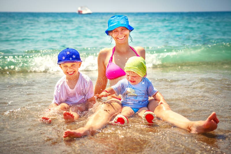 Glückliche Familie, die im Meer badet Lächelnde Mutter mit ihrem Sohn und Tochter auf Strand Sommerferien auf Seestrand lizenzfreie stockbilder Glückliche Familie, die im Meer badet Lächelnde Mutter mit ihrem Sohn und Tochter auf Strand Sommerferien auf Seestrand lizenzfreie stockbilder