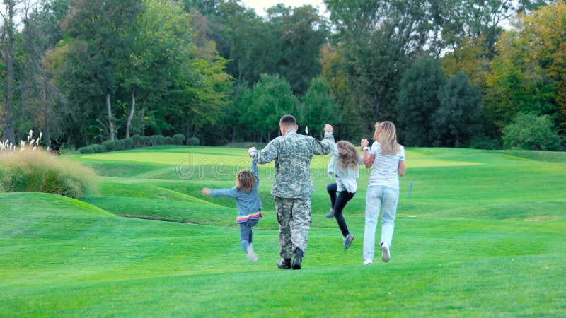 Glückliche Familie, die weg auf Golfplatz geht