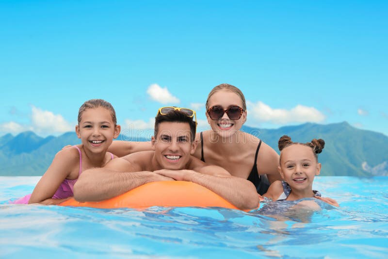 Glückliche Familie im Außenpool im luxuriösen Resort mit schöner Aussicht auf die Berge am sonnigen Tag stockbilder