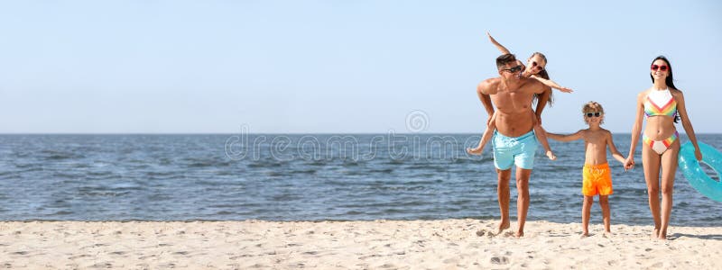 Glückliche Familie mit aufblasbarem Ring am Sandstrand in der Nähe des Meeres für Text. Banner stockbilder