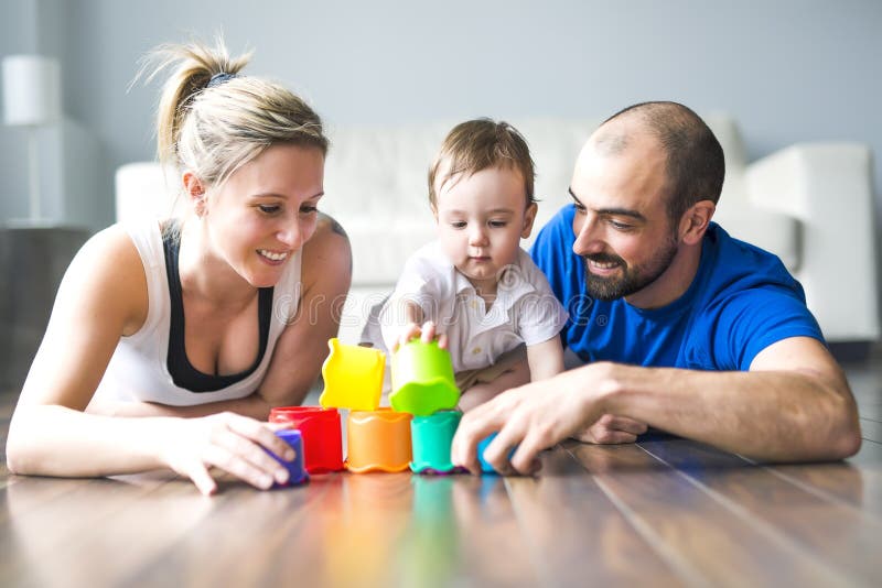 Glückliche Familie mit den Eltern und Sohn, die mit bunten Blöcken im Wohnzimmer spielen