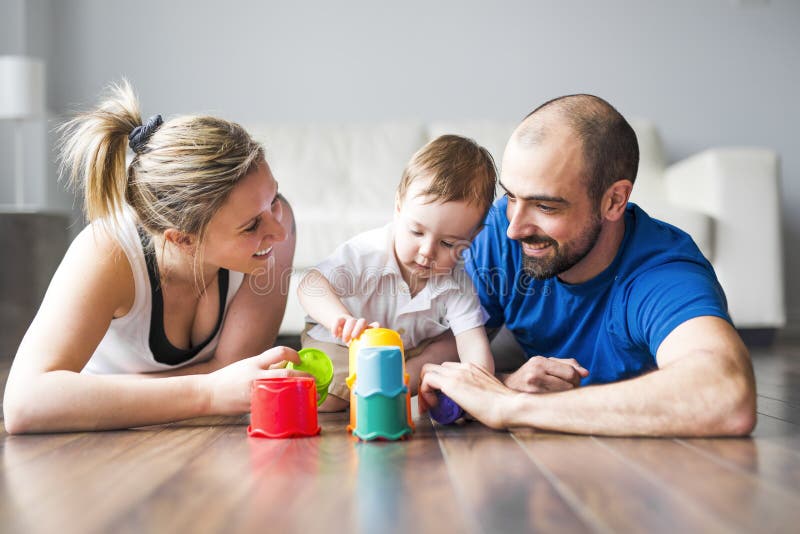 Glückliche Familie mit den Eltern und Sohn, die mit bunten Blöcken im Wohnzimmer spielen