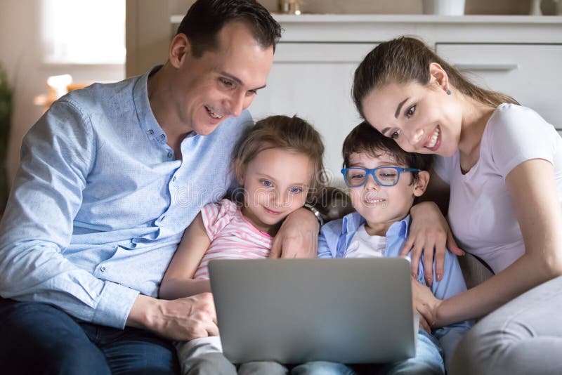 Glückliche Familie mit den Kindern, die lustiges Video auf Bildschirm aufpassen stockfotos