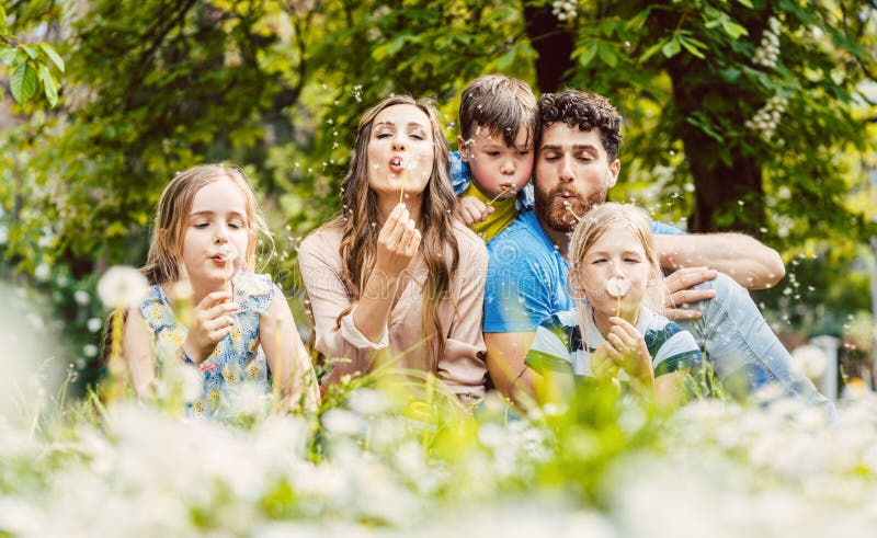 Glückliche Familie sitzend in Hochgras im Frühling blühende Lüster Blumen stockbilder
