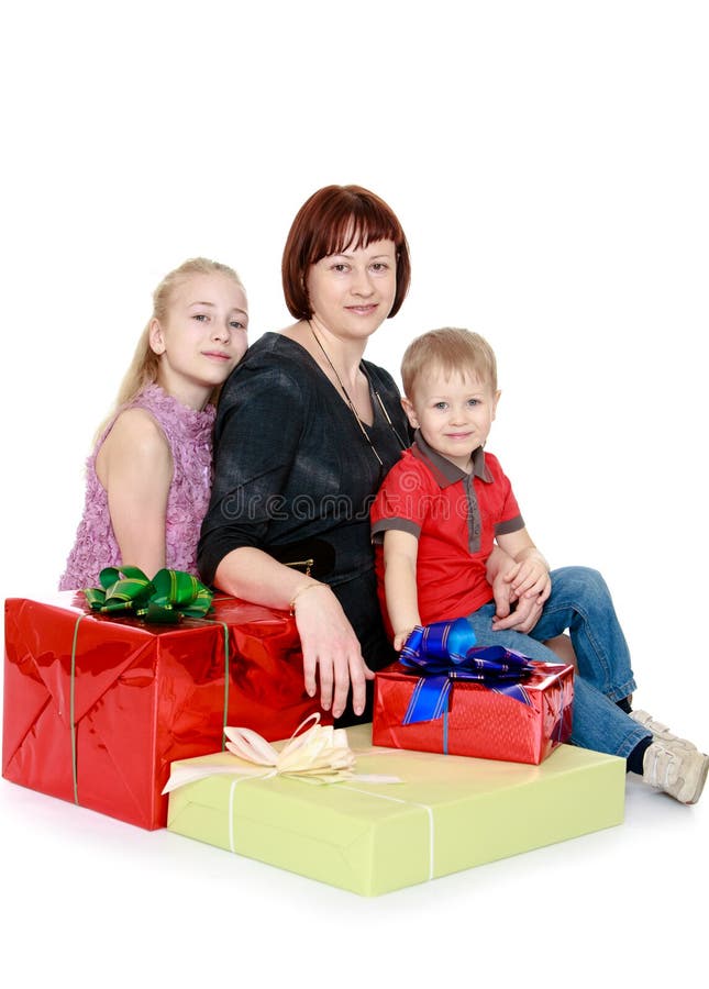 Glückliche Familie sitzt umgeben durch Geschenkmutter lizenzfreies stockfoto Glückliche Familie sitzt umgeben durch Geschenkmutter lizenzfreies stockfoto