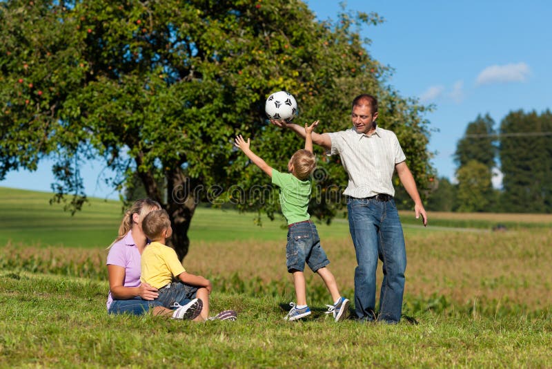 Glückliche Familie spielt Fußball am Sommer stockfotos Glückliche Familie spielt Fußball am Sommer stockfotos