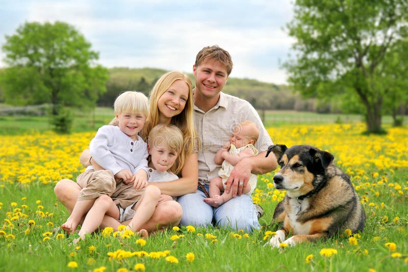Glückliche Familie und Schoßhund in der Blumen-Wiese