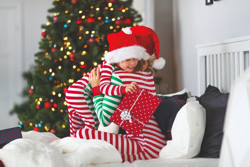 Glückliche Familienmutter ihren Babysohn in den Pyjamas umarmen, die Geschenke O öffnen stockfotografie Glückliche Familienmutter ihren Babysohn in den Pyjamas umarmen, die Geschenke O öffnen stockfotografie