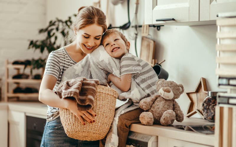 Glückliche Familienmutterhausfrau und -kind in der Wäsche mit Waschmaschine lizenzfreie stockfotografie