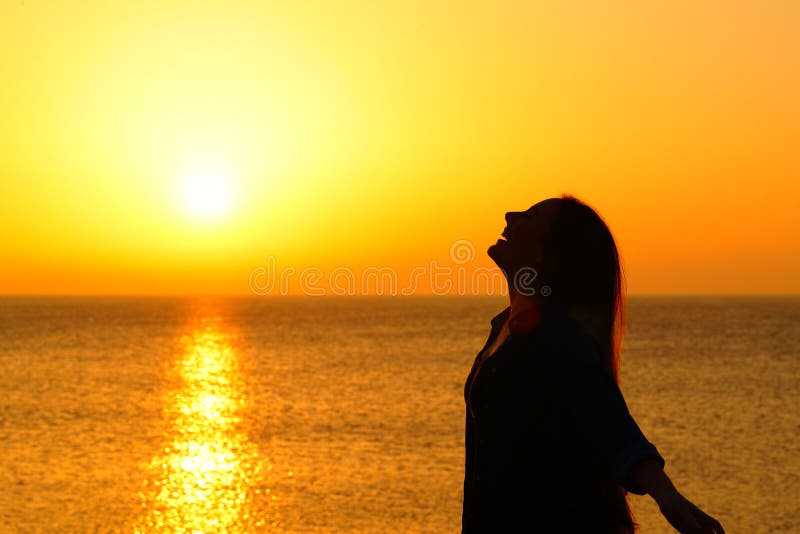 Side view portrait of a happy woman silhouette on the beach breathing at sunset. Side view portrait of a happy woman silhouette on the beach breathing at sunset