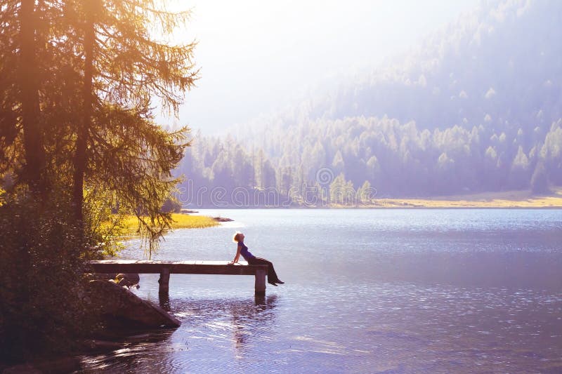 Glückliche Frau, die auf dem Pier- und Lächeln, Glück- oder Inspirationskonzept sitzt lizenzfreie stockfotografie