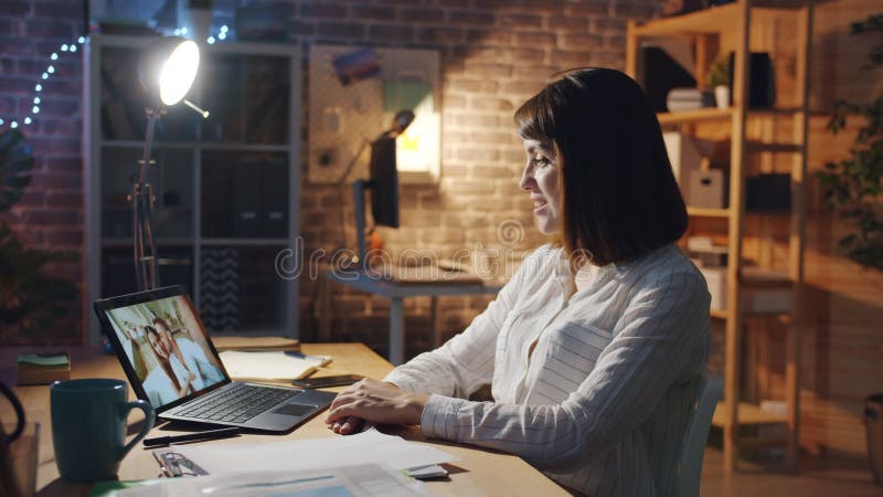 Glückliche Frau, die auf den Laptop-Bildschirm im Büro schaut und über Skype kommuniziert